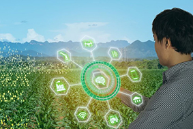 Composite image of person facing a field, holding a mobile phone, with mountains in background and digital data overlaid on the mobile device.