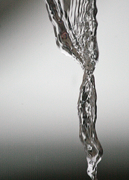A black & white closeup photo of water dripping out of a tap.