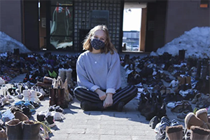 Ally Zaheer sits cross-legged wearing a mask and surrounded by hundreds of pairs of shoes outside city hall in Pickering