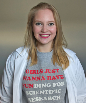A photograph of graduate student Nikola May smiling and wearing a shirt that says 'Girls just wanna have funding for scientific research'