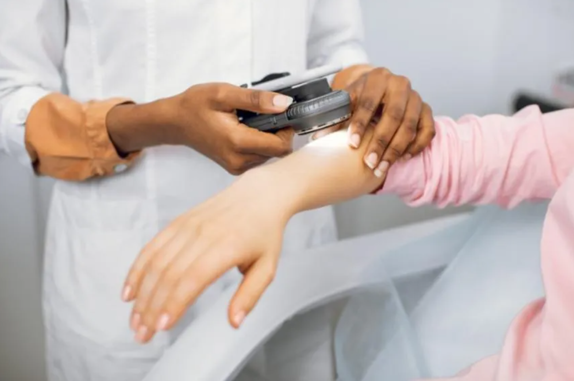 Doctor assessing patient's arm with magnifying glass