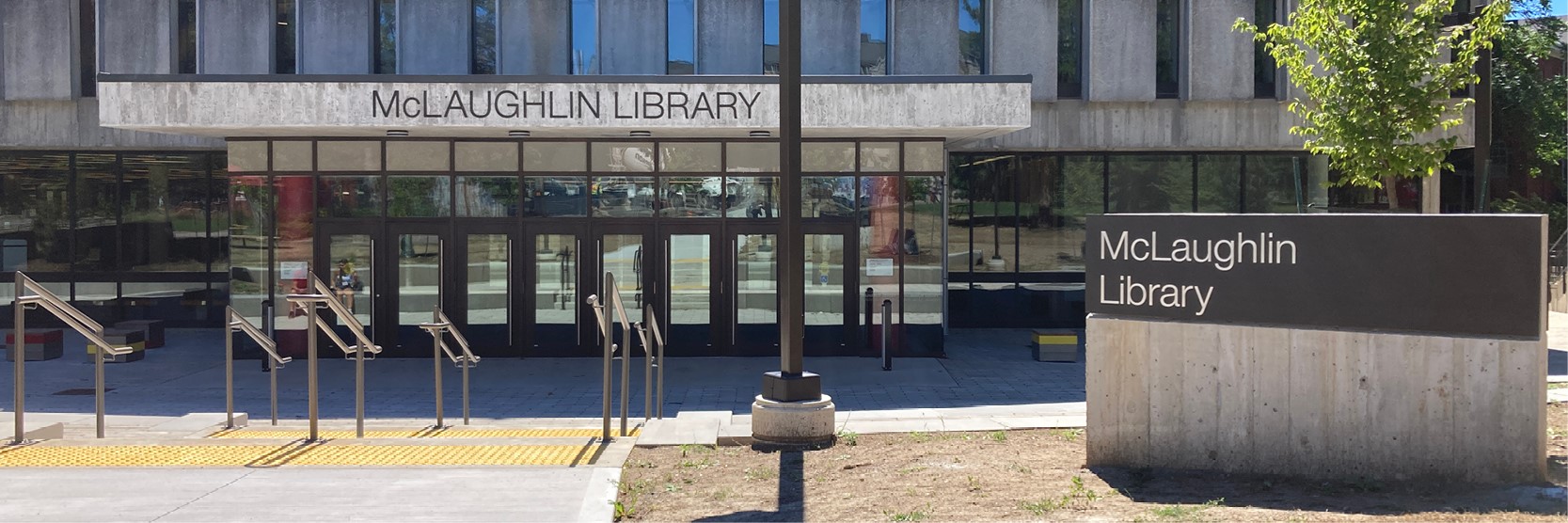 New McLaughlin Library entrance. The concrete slab above the entrance says McLaughlin Library, and steps lead to eight entrance doors.
