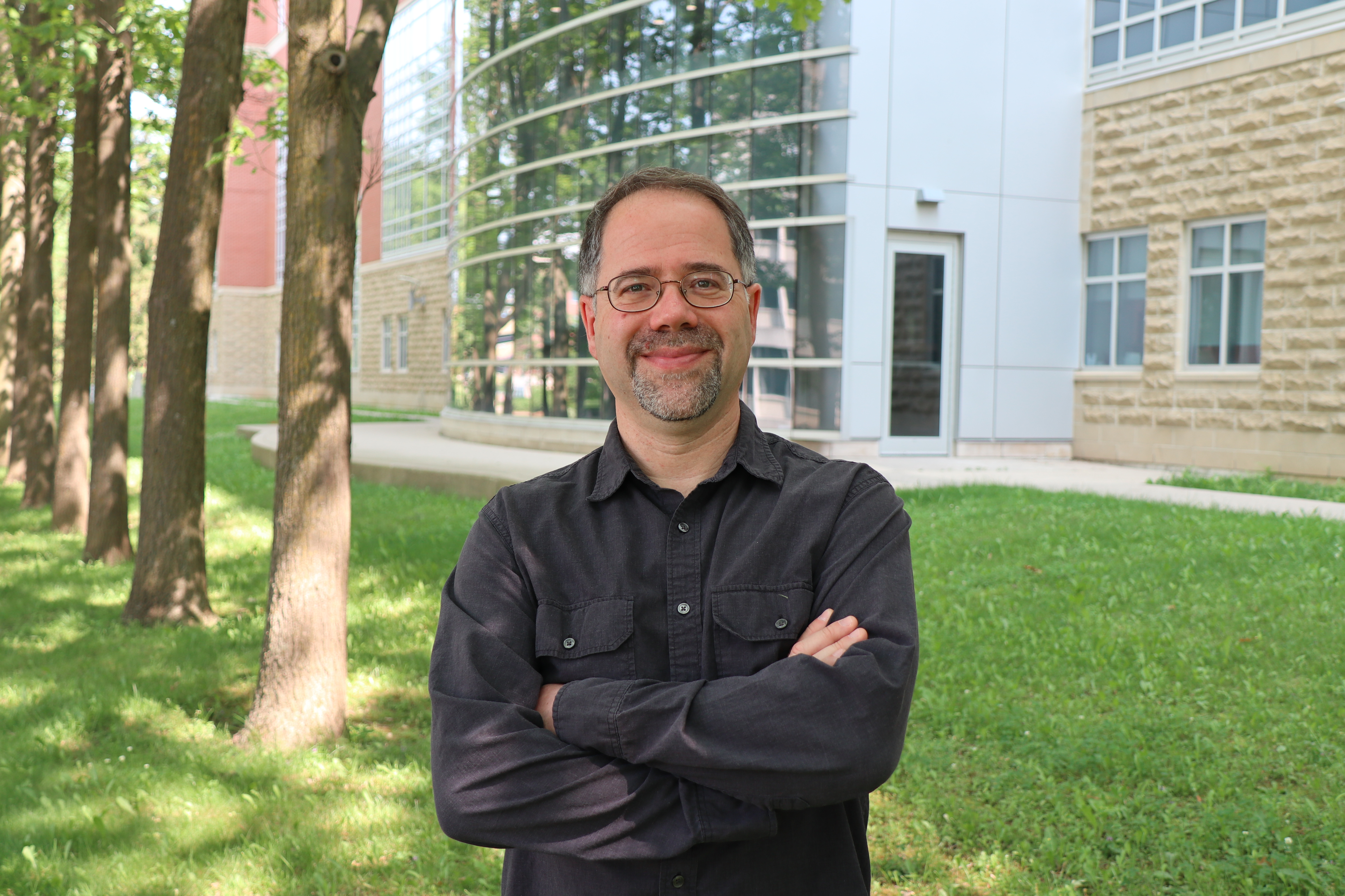 Dr. Leonid Brown standing with arms crossed and smiling a camera outside the Summerlee Science Complex