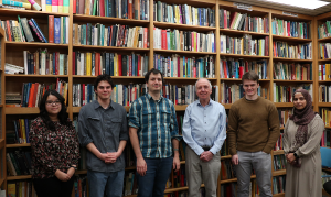 Group of researchers posing for camera in front of large bookshelf.