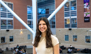 Student smiling for camera on second floor of SSC with the atrium in her background.