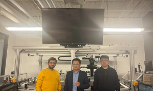 Group of researchers posing for camera in front of large TV monitor.